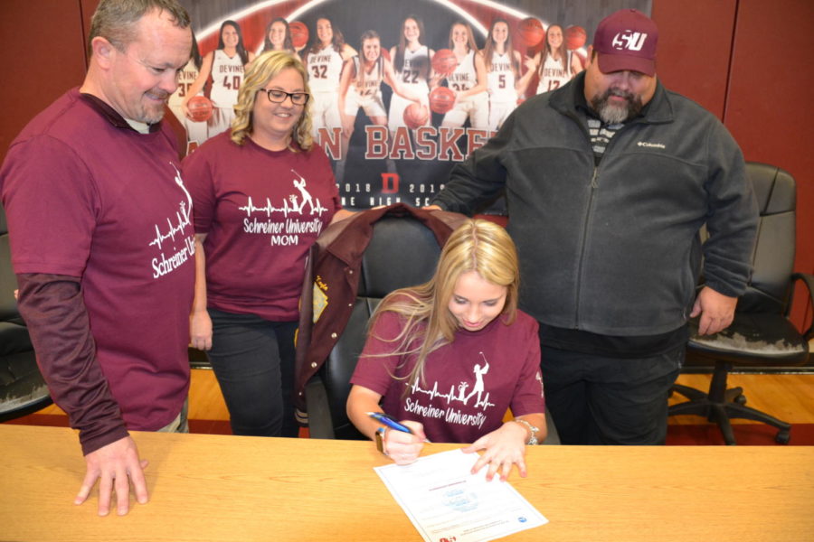 Kayla Signs with her family and coach standing behind her.