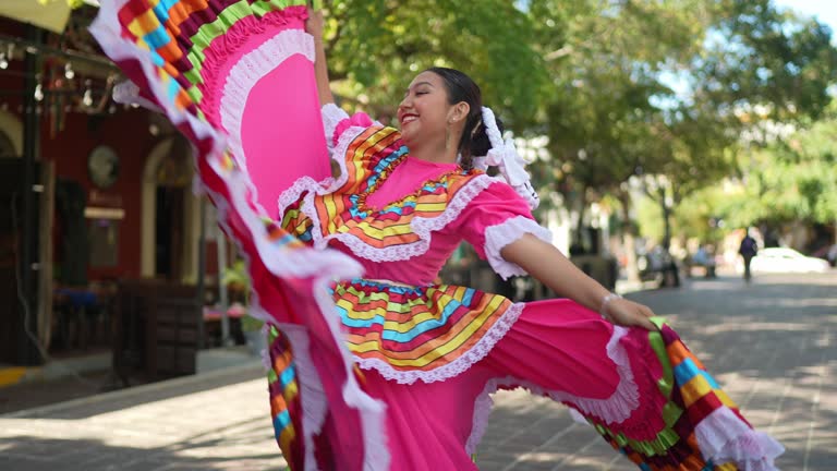 A young woman dancing outdoors wearing traditional Mexican attire.